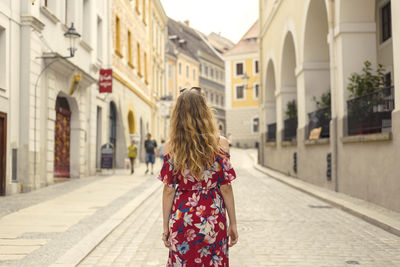 Rear view of woman standing on street in city