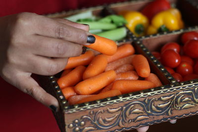 Midsection of woman holding container with various vegetables