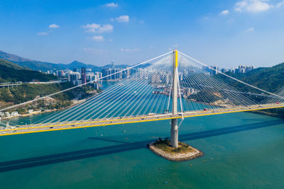 Suspension bridge over sea against blue sky during sunny day