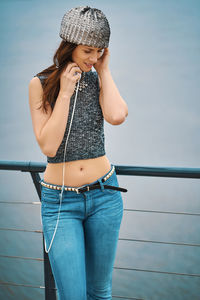 Full length of woman standing by railing against sea