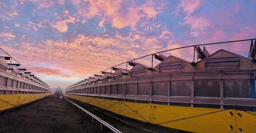 Train on railroad tracks against sky during sunset