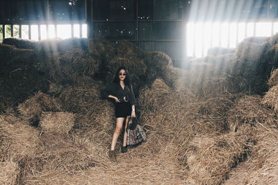 Portrait of woman standing by hay bales in shed