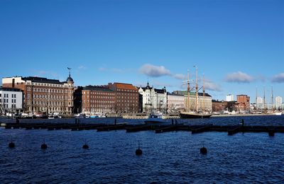 Buildings at waterfront against cloudy sky