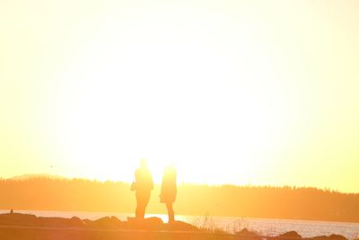 Silhouette people standing against clear sky during sunset