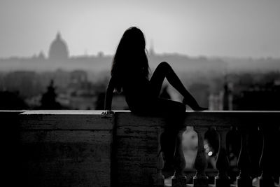 Silhouette of woman sitting on railing