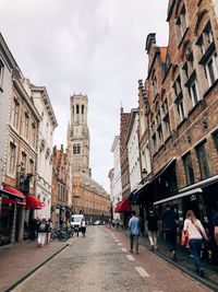 People walking on street amidst buildings in city