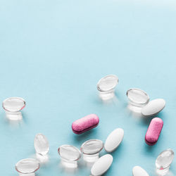 Close-up of pills spilling from bottle against white background