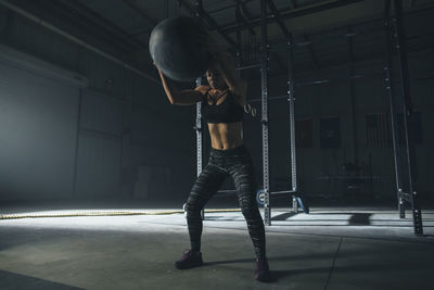 Female athlete exercising with fitness ball in gym