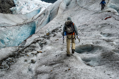 Rear view of hiker walking on glacier