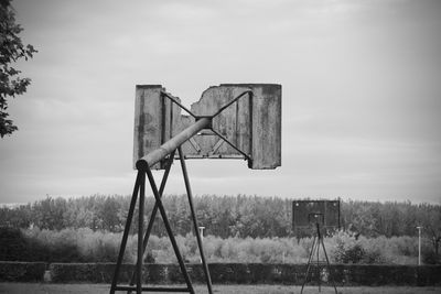 Basketball hoop on field by lake against sky