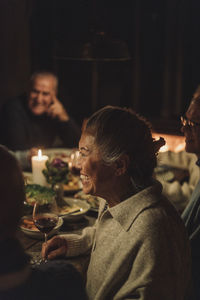 Side view of happy senior woman enjoying candlelight dinner party