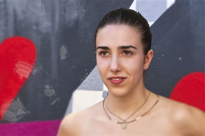 Portrait of young woman standing against wall