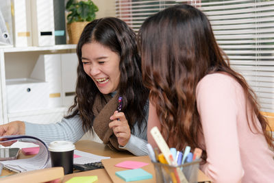 Portrait of young woman using mobile phone while sitting at restaurant