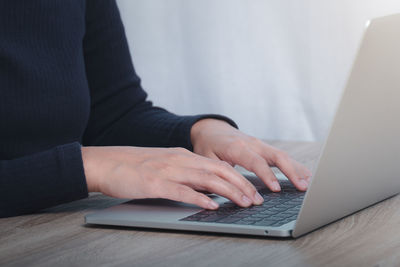 Midsection of woman using laptop on table