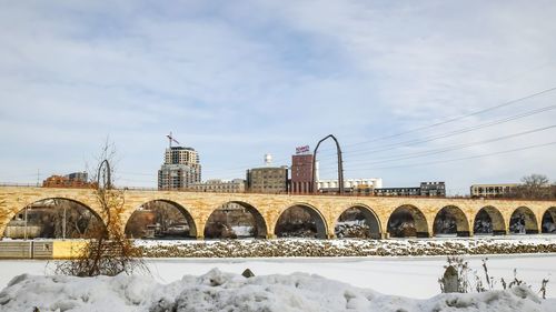 Snow covered arch bridge against sky