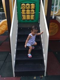 Full length of cute baby girl playing on staircase at playground