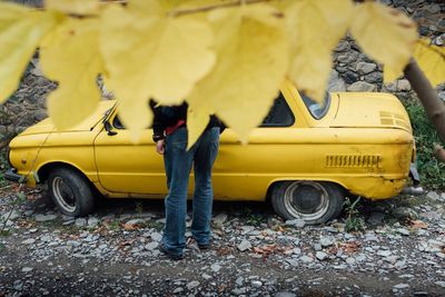 Man standing by yellow car on street