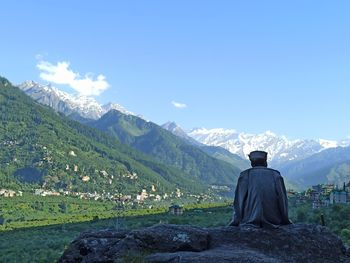 Rear view of man looking at mountains against sky