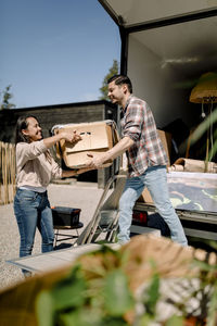 Couple unloading box from truck while relocating to new house