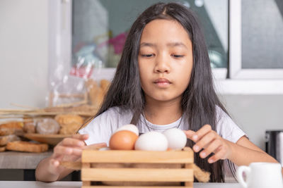 Close-up of girl holding egg at kitchen