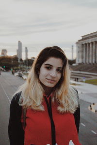 Portrait of young woman standing against built structure