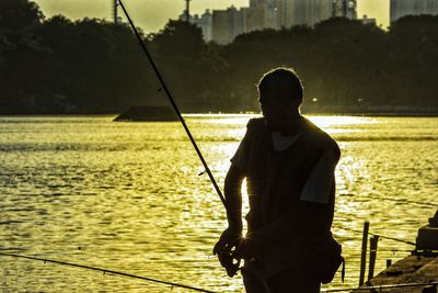 Silhouette man fishing in river