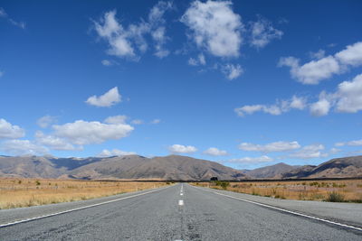 Road leading towards mountains against sky