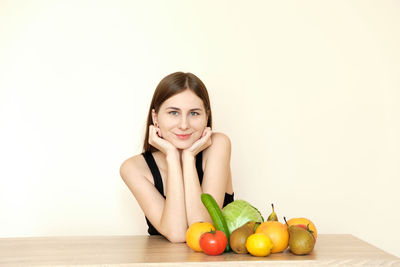 Portrait of young woman with fruits against white background