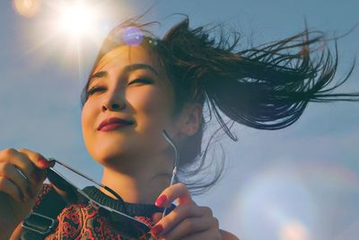 Portrait of young woman holding hands against sky