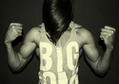 Young muscular man flexing muscles by wall
