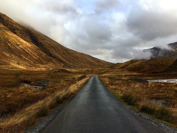 Empty road amidst landscape against sky