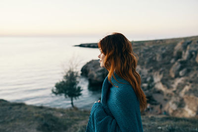 Woman looking at sea against sky during sunset