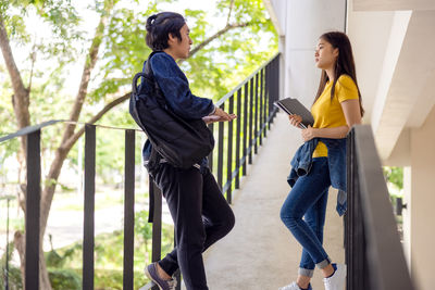 Two asian university students walking and conversing to class in a magnificent campus building