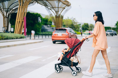 Side view of mother and daughter walking on road