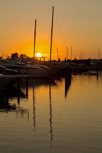 Boats moored in harbor at sunset