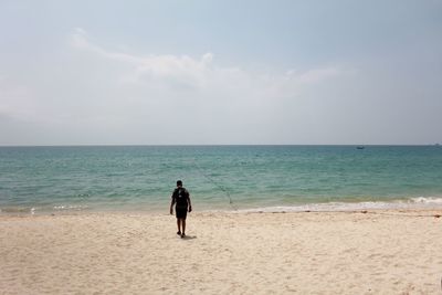 Rear view of woman on beach against sky