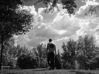 Rear view of man on field against sky