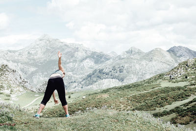 Rear view of woman standing on mountain against sky