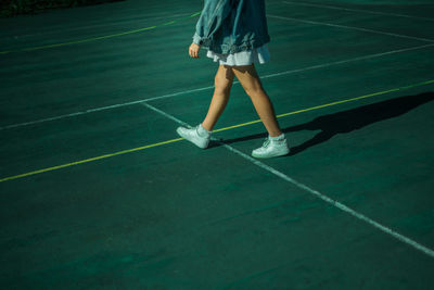 Low section of young woman walking in tennis court