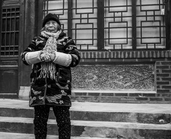 Portrait of woman standing against building in city