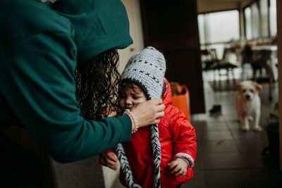 Midsection of mother touching baby with dog in background at home