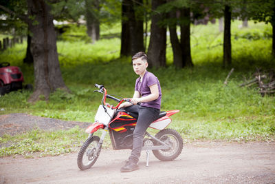 Full length of boy sitting on dirt bike