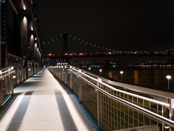 Illuminated bridge over river against sky at night