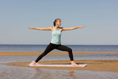 Side view of woman exercising at beach