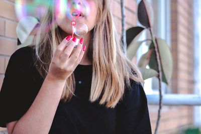 Midsection of woman blowing bubbles