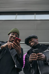 Black friends using smartphones on street