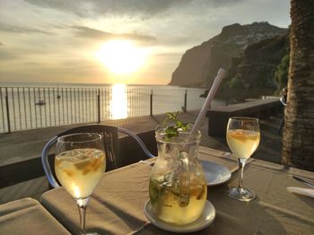 Wine glass on table against sky during sunset