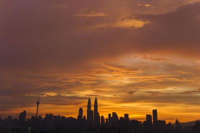 Silhouette of cityscape against orange sky during sunset