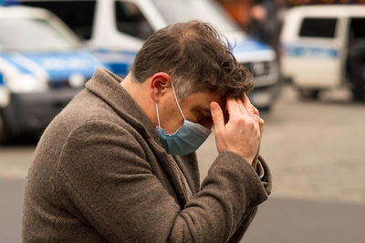 Man wearing a protective mask with his hands on his head due to receiving bad news or a headache