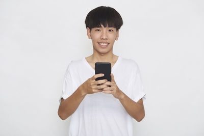 Young man using smart phone against white background